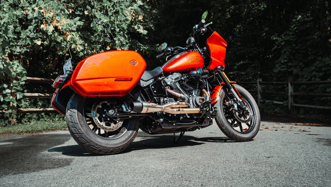 Red Harley-Davidson Softail Low Rider ST equipped with Sawicki Speed Shorty 2-into-1 exhaust parked on a road in front of trees.