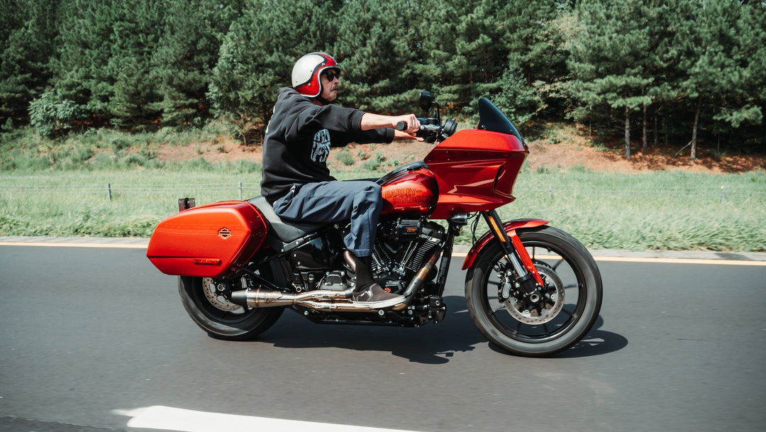 Red Harley-Davidson Softail Low Rider ST equipped with Sawicki Speed Shorty 2-into-1 exhaust being ridden on a country road.