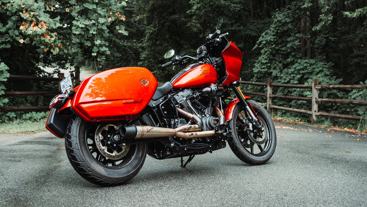 Red Harley-Davidson Softail Low Rider ST equipped with Sawicki Speed Mid-Length 2-into-1 exhaust parked on a road in front of trees.