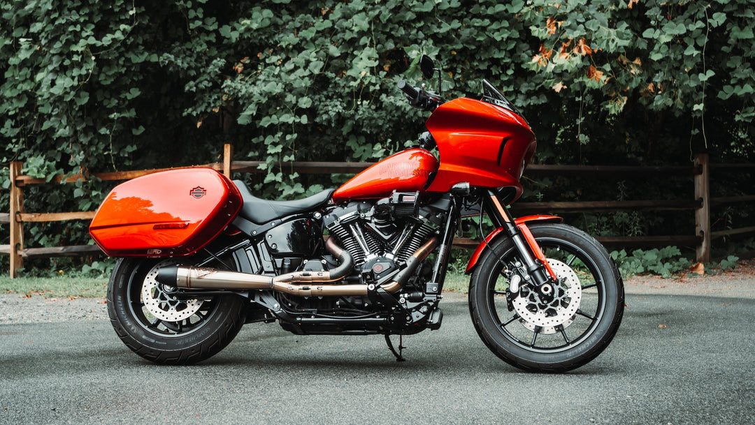 Red Harley-Davidson Softail Low Rider ST equipped with Sawicki Speed Mid-Length 2-into-1 exhaust parked on a road in front of trees.