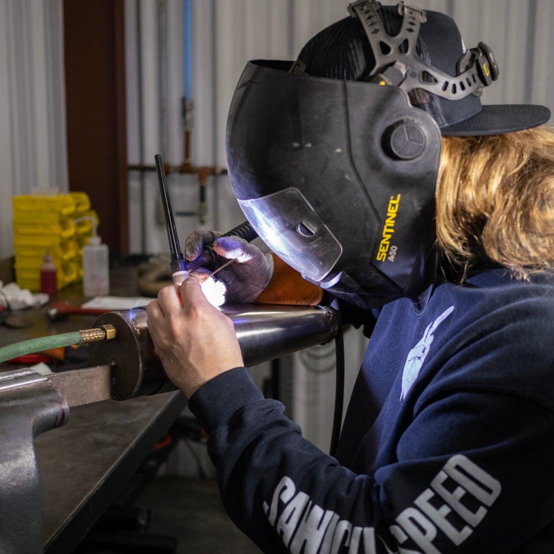 A welder using back purging while welding a motorcycle exhaust